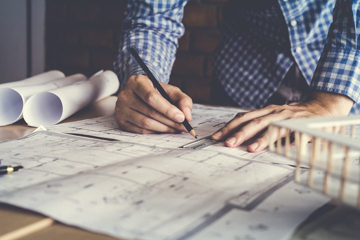 Person planning and writing out blueprints for a building